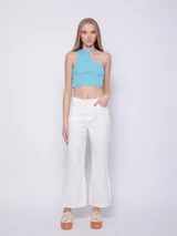 Top corto blanco de punto, sin mangas, con cuello halter asimétrico.