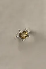 Anillo de plata 925 con banda chata, piedra citrino facetada central de corte brillante y detalles de esferas decorativas alrededor del engaste.