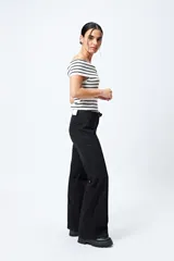 Jean negro de calce flare con cinturón incorporado en la misma tela y silueta ajustada en cadera que se ensancha hacia el ruedo.