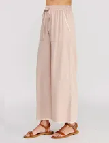 Pantalón palazzo de lino color beige, de tiro alto y silueta suelta, con cintura elastizada y cordón de ajuste. Cuenta con detalles de ribetes bordados festoneados en contraste en los bolsillos y en el ruedo.