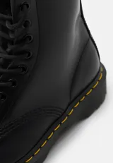 Botas de cuero negro con diseño clásico de 8 ojales, costuras amarillas en la suela y suela de goma acanalada con amortiguación de aire.
