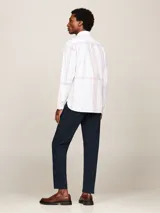 Camisa blanca de algodón con estampado de cuadros en tonos rojo y azul, corte regular, cuello abotonado, bolsillo de parche en el pecho, mangas largas con puños abotonados y logo de Tommy Hilfiger bordado en el puño.