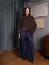 Poncho tejido asimétrico color bordó, con detalle de lentejuelas sutiles y flecos en el ruedo.