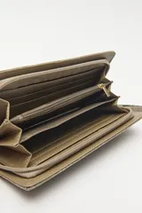 Billetera de mano con textura efecto cocodrilo, color beige, con cierre perimetral y tira de muñeca desmontable.