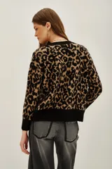 Sweater de punto con estampado animal print en tonos negro y tostado, de cuello redondo y mangas largas con puños acanalados.