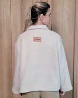 Chaqueta de textura bouclé en color bordó, con corte oversize, cuello camisero, cierre frontal y bolsillos laterales.