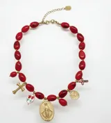 Collar corto compuesto por cuentas de resina en color rojo y dijes de acero, incluyendo una medalla de la Virgen Milagrosa, una cruz y un dije de flores. Cuenta con cierre de mosquetón y cadena de alargue.