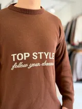 Sweater de punto color beige con cuello redondo, manga larga y diseño estampado en el pecho con las frases "TOP STYLE" y "follow your dreams" en color marrón.