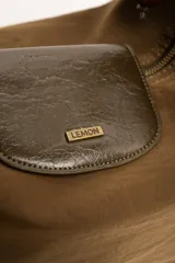 Cartera tipo shopper color marrón, con solapa frontal decorativa en tono más oscuro y tiras con nudos. Incluye herrajes dorados y un charm colgante con cuentas de madera.