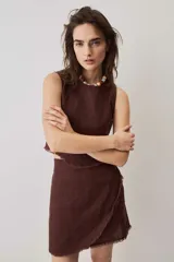 Blusa cropped color chocolate, de silueta suelta y cuello redondo, con terminación de bordes deshilachados.