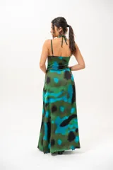 Vestido largo con estampado abstracto en tonos verdes, azules y negros. Presenta tirantes finos y cuello halter cruzado con detalle de abertura en el pecho.