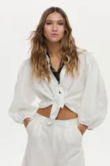 Camisa de lino blanca con mangas abullonadas y diseño para anudar al frente.