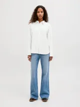 Camisa de popelín blanca de manga larga con cuello clásico y cierre frontal de botones ocultos, de ajuste relajado y puños anchos.