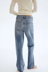 Jeans de cinco bolsillos en denim de algodón con leve stretch, tiro alto y cierre de botón. Corte ajustado de cintura a muslo, y pierna ancha (bootcut) desde la rodilla hasta el bajo. Presenta un lavado celeste medio con efecto desgastado.