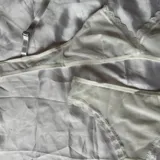 Conjunto de lencería de dos piezas color blanco, confeccionado en tela suave y semitransparente con detalles de encaje en los bordes. Incluye un bralette triangular sin aro ni relleno, con breteles regulables y una bombacha vedetina a juego.
