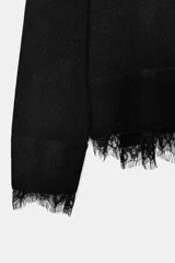 Jersey de cuello redondo y manga larga, confeccionado en tejido de punto fino. Presenta un diseño minimalista con un detalle de aplicación de encaje a tono en el bajo y en los puños.