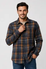 Sobrecamisa de franela a cuadros en tonos azul marino, marrón y gris, de manga larga, con bolsillos frontales con solapa y cierre de botones.
