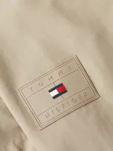 Campera Tommy Hilfiger color beige con cuello alto y cierre de cremallera. Tiene dos bolsillos laterales, detalles distintivos de la marca y logo engomado bordado en la manga.