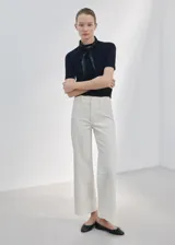 Jeans estilo wide leg de tiro alto en color crudo, con diseño de pernera ancha, trabillas para cinturón y costuras frontales marcadas.