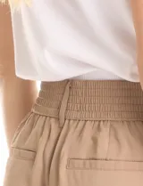 Pantalón tipo palazzo de corte ancho y fluido, confeccionado en tejido sastrero. Presenta tiro alto con doble abotonadura frontal, pinzas decorativas y cintura elástica en la parte posterior. Incluye bolsillos laterales funcionales.