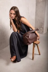 Cartera tipo bolso de cuero color marrón, con diseño amplio y suave, doble correa de hombro y correa regulable y desmontable. Cuenta con cierre metálico superior, bolsillo interior con cierre y compartimento para celular.
