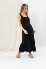 Vestido midi de tejido tipo seda con caída fluida, escote redondo y sin mangas. Presenta un diseño minimalista con detalle de flecos en el ruedo.