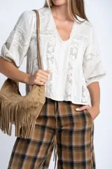 Blusa color crudo de manga corta abullonada, con escote en V y detalles de encaje y bordados verticales en el frente y mangas.