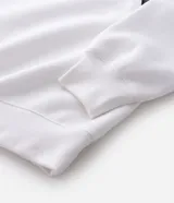 Buzo deportivo de felpa en color blanco con detalles en negro. Presenta cuello tipo polo, mangas largas con puños acanalados y diseño con recortes laterales. Incluye estampados gráficos en el frente con tipografía cursiva y emblema circular.
