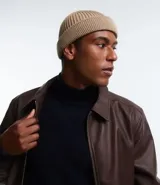 Gorro tipo fisherman de tejido acrílico con textura acanalada, diseño corto y etiqueta pequeña con logo en el frente.