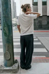 Top de cuello redondo y manga corta con diseño de capas que combina una remera de algodón blanca con un chaleco de punto gris superpuesto. Presenta detalles de botones joya en el hombro.