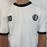 Remera de tejido de punto color blanco con detalles en negro en cuello y mangas. Presenta un diseño estampado en la espalda que incluye el número 10, las siglas VCP y un recuadro con la inscripción 2015-infinito.