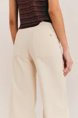 Jean de tiro alto y silueta acampanada color beige, confeccionado en algodón, con diseño ajustado en la cadera y corte amplio hacia los tobillos.
