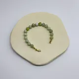 Pulsera de cuentas de serpentina natural de 8 mm, con separadores de nudos de hilo verde y cierre de mosquetón con baño de oro.