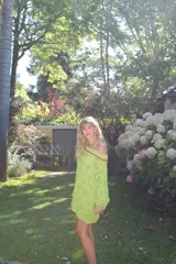 Vestido corto calado color terracota, con escote amplio y mangas largas. Incluye un accesorio tejido que puede usarse como collar o cinturón.