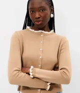 Cardigan de punto marrón de manga larga, con cierre frontal de botones y detalles de encaje blanco en el cuello redondo y los puños.