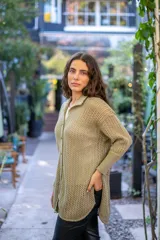 Camisa de punto calado en color beige con hilo de lurex. Presenta una silueta oversize, cuello camisero clásico, mangas 3/4 ligeramente abullonadas y cierre frontal con botones metálicos.