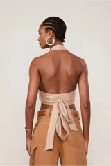 Top halter color beige confeccionado en lino, con escote en V cruzado, tiras medianas y lazada en el frente.