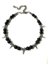 Gargantilla de diseño punk con piedras volcánicas negras, esferas de hematite y dijes de pinchos metálicos, montada sobre cadena de acero quirúrgico.