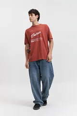 Remera blanca de manga corta con estampado frontal que incluye la palabra 'Savior' en letras cursivas negras y otros textos en tipografía sans-serif. Corte regular.