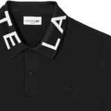 Remera tipo polo Lacoste de manga corta, confeccionada en tejido piqué de algodón. Presenta cuello con diseño jacquard con el nombre de la marca en contraste y cierre frontal de dos botones. Incluye el logo de la marca bordado en el pecho en tono sobre tono.