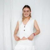 Chaleco corto con estampado abstracto en tonos dorados y azules, escote en V y cierre frontal con botones de madera.