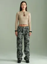 Pantalón de corte recto y tiro medio-alto, confeccionado en algodón grueso con apariencia de denim. Presenta un estampado abstracto en tonos grisáceos y negros, con bolsillos delanteros y traseros.