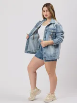 Campera de jean celeste con detalles de roturas, corte oversize, cuello clásico, cierre con botones metálicos, bolsillos frontales con solapa y puños abotonados.