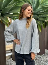 Blusa gris de lurex con cuello alto y mangas largas abullonadas.