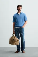 Polo de manga corta, color azul medio, tejido en punto perlado con cuello solapa y cierre frontal de cremallera.