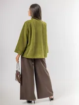 Chaqueta tipo capa confeccionada en paño, con cuello alto, cierre frontal de botones grandes y mangas amplias. Cuenta con bolsillos laterales y forro interior.