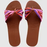 Sandalias tipo chinela Havaianas modelo You St Tropez, con base de goma color marrón y tira superior de tela con diseño de lazo estampado a rayas multicolor.