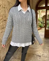 Sweater de punto gris con diseño de ochos, escote en V y mangas largas.