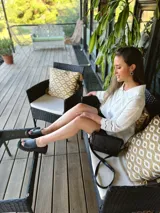 Cartera bandolera de cuero negro con textura tipo cocodrilo, correa larga regulable y forro interno de tela.