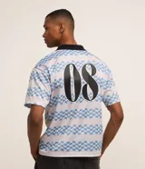 Remera masculina con cuello polo y manga corta, confeccionada en tejido con tecnología dry y estampado a rayas con lettering. Diseño boxy sportcore con cuello polo negro.